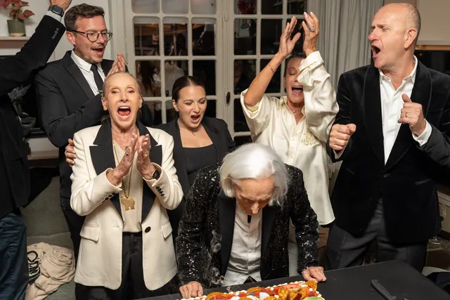 La famiglia e gli ospiti, in bianco e nero, applaudono Mémé mentre festeggia i suoi 100 anni