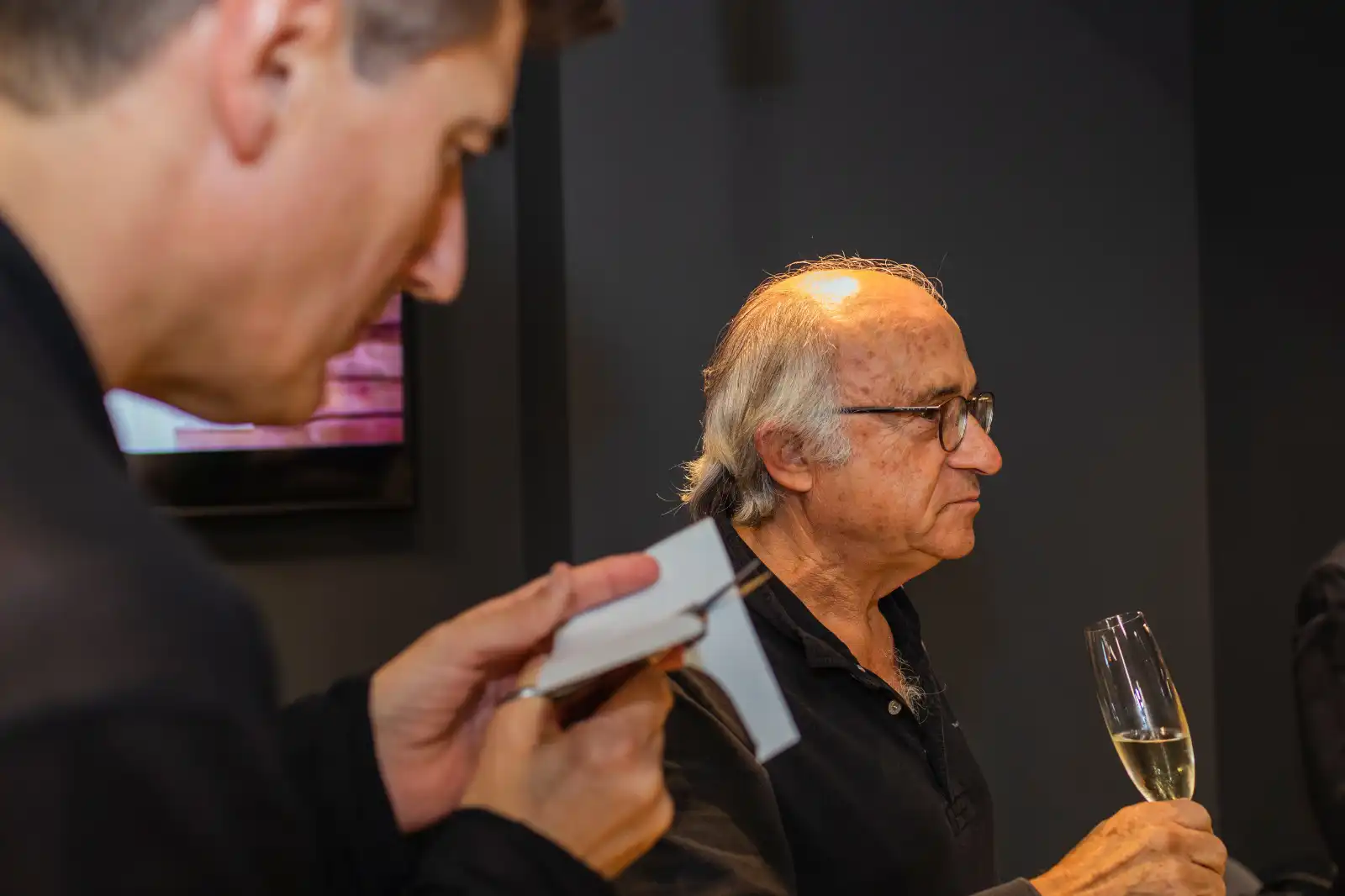 Un ospite con un calice di champagne mentre Igor Kucinic ritaglia un ritratto silhouette a un cocktail